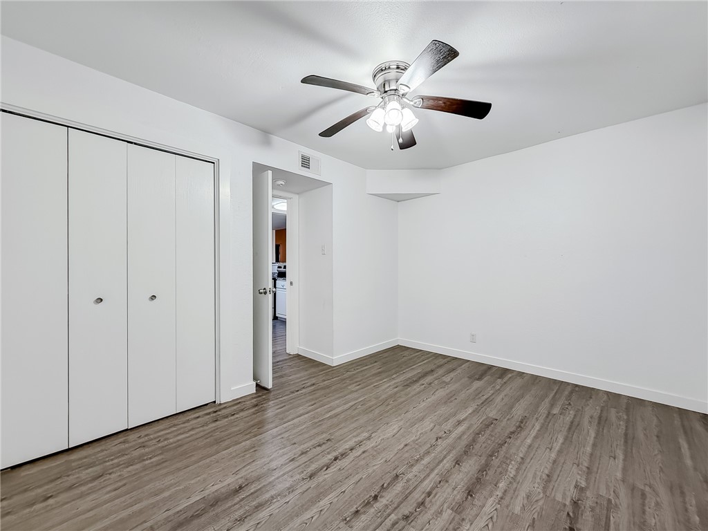 302 Easy Street, Unit B Corpus Christi, TX 78418 - Photo 16 of 27 an empty room with wooden floor chandelier fan and windows