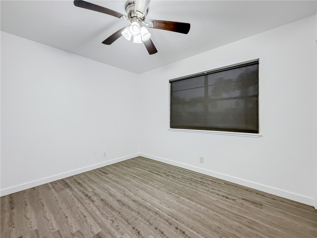 302 Easy Street, Unit B Corpus Christi, TX 78418 - Photo 17 of 27 an empty room with wooden floor and windows
