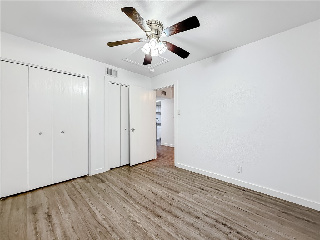 302 Easy Street, Unit B Corpus Christi, TX 78418 - Photo 18 of 27 an empty room with wooden floor ceiling fan and windows
