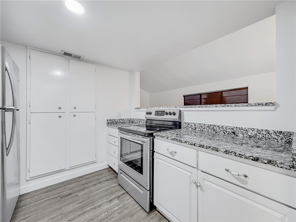 302 Easy Street, Unit B Corpus Christi, TX 78418 - Photo 10 of 27 a kitchen with granite countertop white cabinets and white appliances