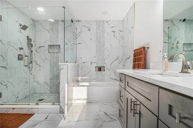 a bathroom with a granite countertop sink mirror shower and bathtub