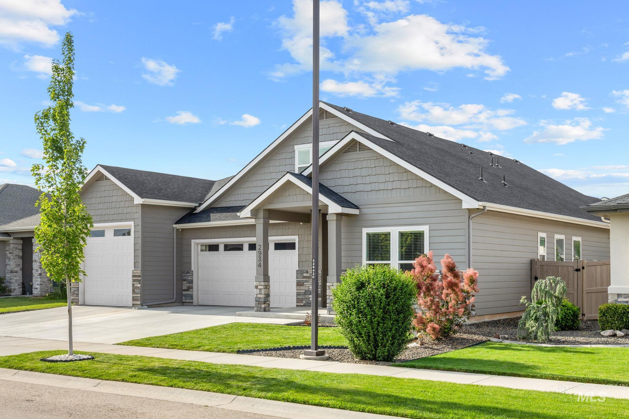 2934 East Murchison Street Meridian, ID 83642 - Photo 3 of 44 Contemporary residence featuring a four car garage with white paneled doors, gray horizontal siding, and stone accents