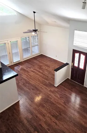 a view of kitchen and empty room with wooden floor