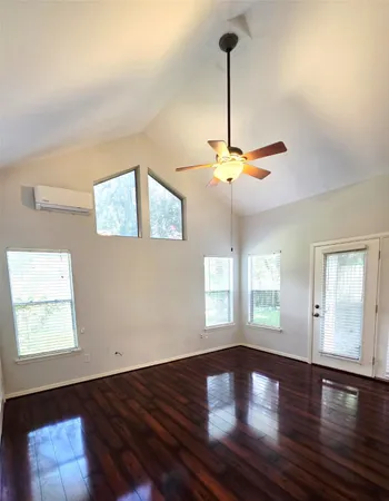 a view of empty room with wooden floor and fan