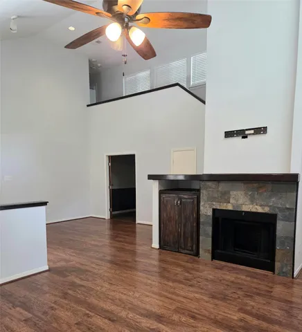 a view of an empty room with wooden floor and a fireplace