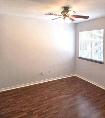 a view of a room with wooden floor and a ceiling fan