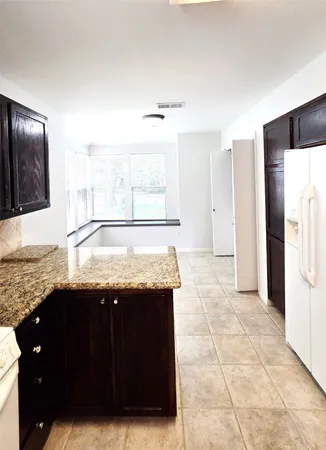 a kitchen with granite countertop a sink and a refrigerator