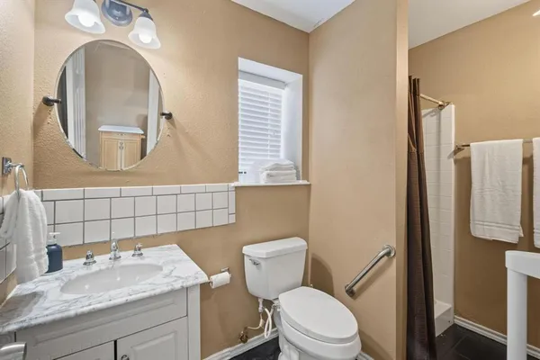 a bathroom with a granite countertop toilet sink and mirror