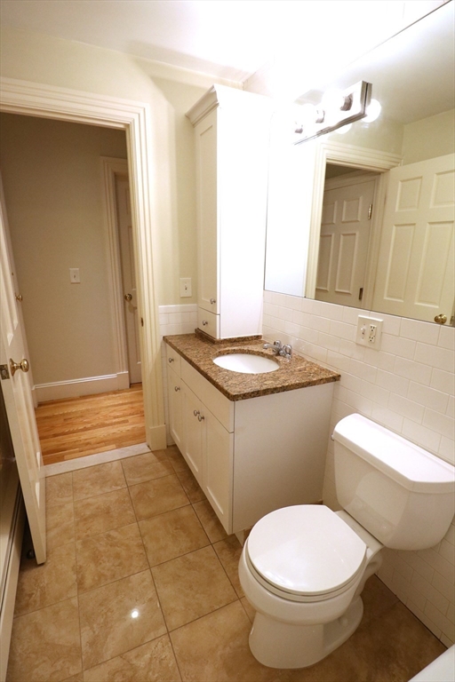 8 Caldwell Avenue, Unit 2 Somerville, MA 02143 - Photo 12 of 16 a bathroom with a granite countertop toilet a sink and a mirror