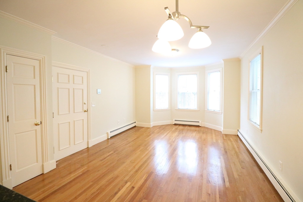 8 Caldwell Avenue, Unit 2 Somerville, MA 02143 - Photo 4 of 16 an empty room with wooden floor and windows