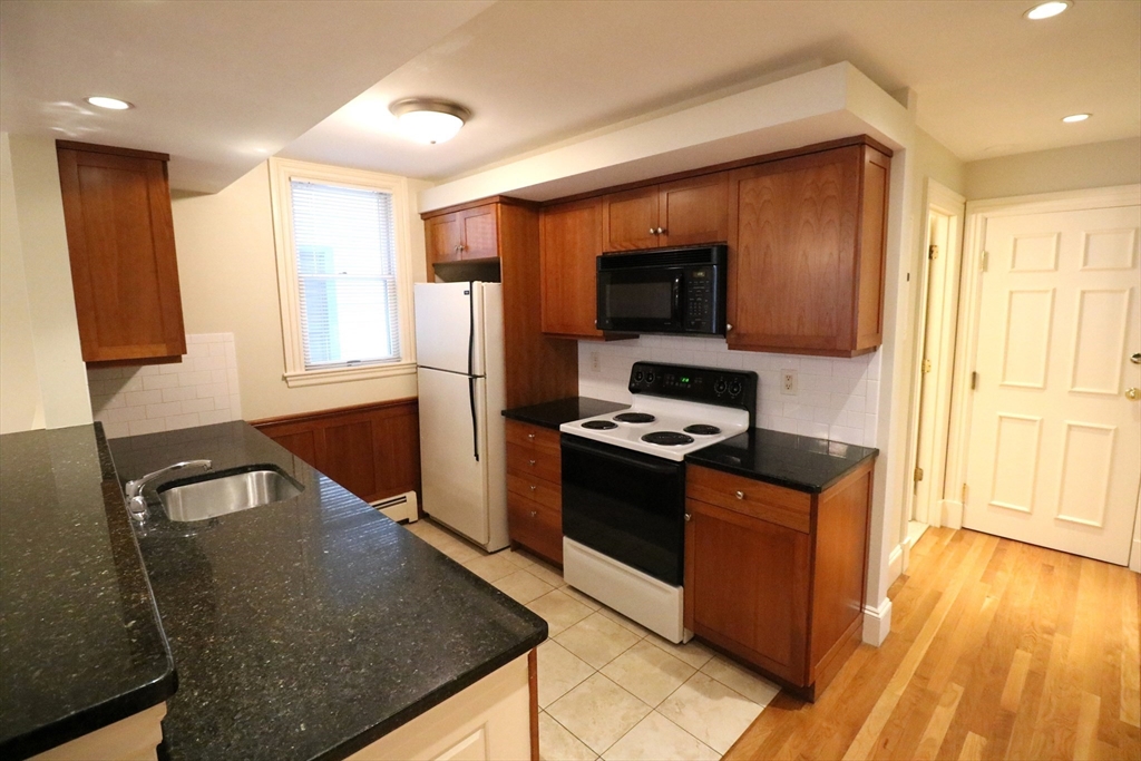 8 Caldwell Avenue, Unit 2 Somerville, MA 02143 - Photo 7 of 16 a kitchen with stainless steel appliances granite countertop a stove a sink and a microwave