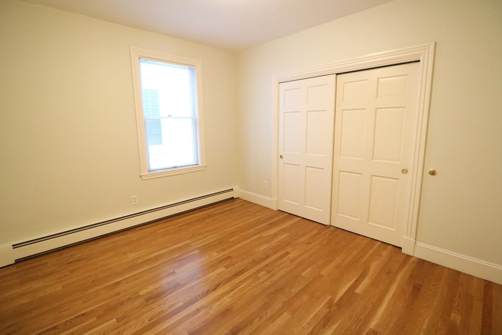 8 Caldwell Avenue, Unit 2 Somerville, MA 02143 - Photo 9 of 16 an empty room with wooden floor and a window