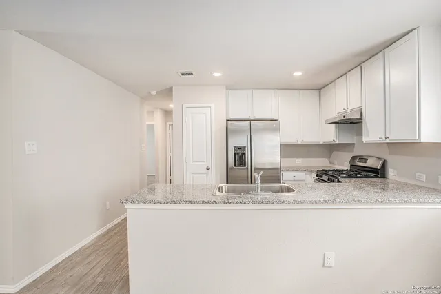 a kitchen with stainless steel appliances granite countertop a sink a stove a refrigerator a microwave and cabinets