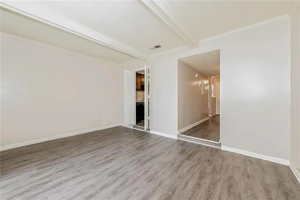 a view of an empty room with wooden floor and closet