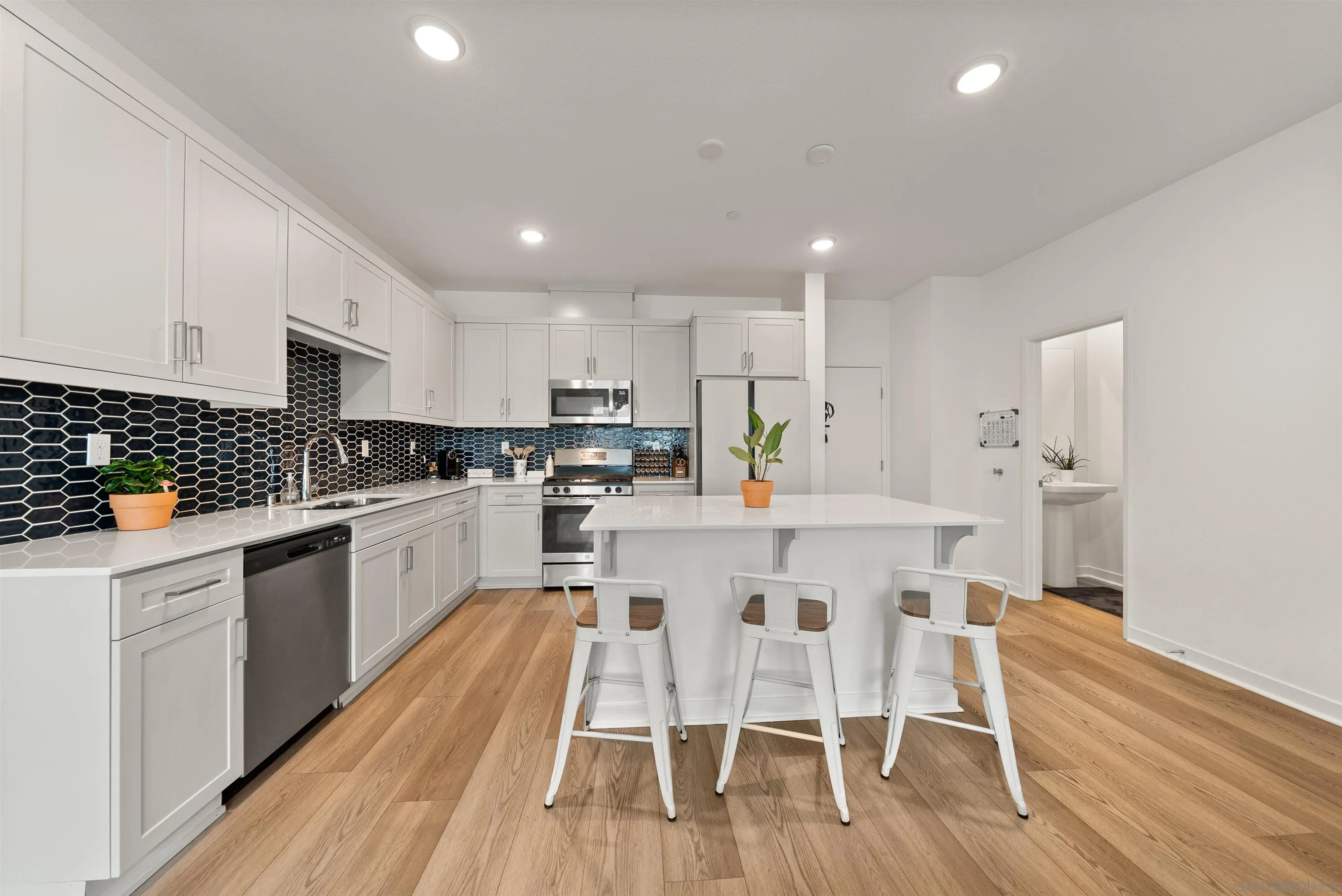 323 Satsuma Trail Fallbrook, CA 92028 - Photo 6 of 28 a kitchen with white cabinets stainless steel appliances and dining table