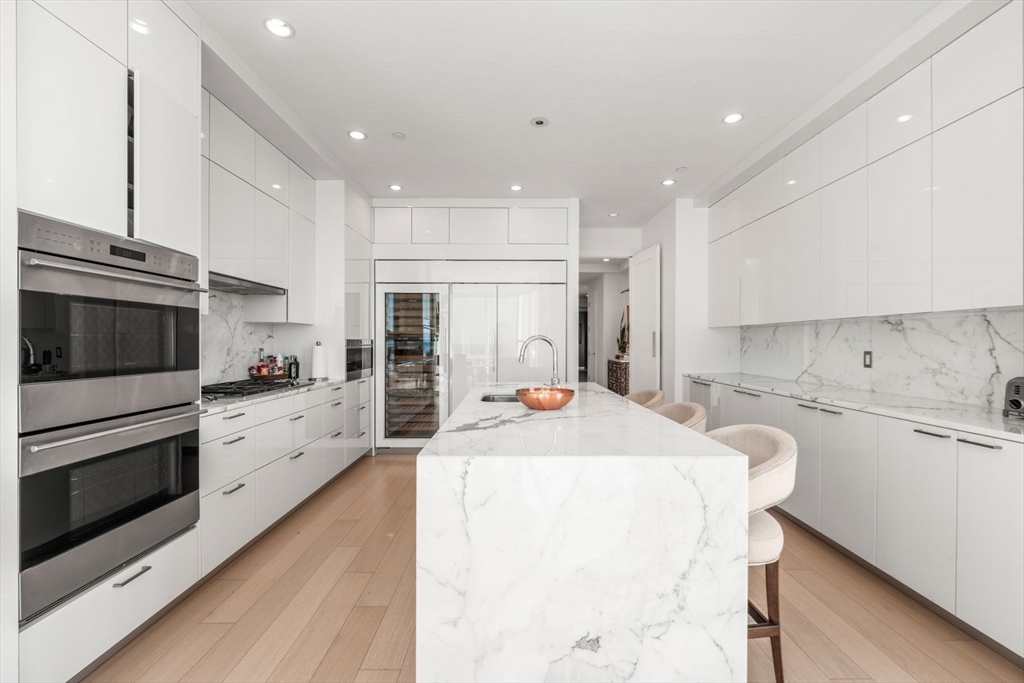 1 Franklin Street, Unit 5002 Boston, MA 02110 - Photo 14 of 40 a large kitchen with stainless steel appliances kitchen island granite countertop a stove a sink a refrigerator and white cabinets with wooden floor
