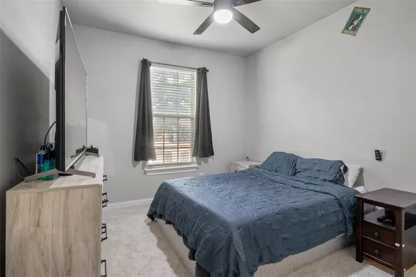 a bedroom with a bed and a flat tv screen on dresser