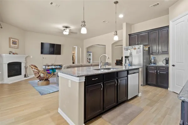 a kitchen with stainless steel appliances granite countertop a refrigerator a sink dishwasher a oven and a dining table with wooden floor