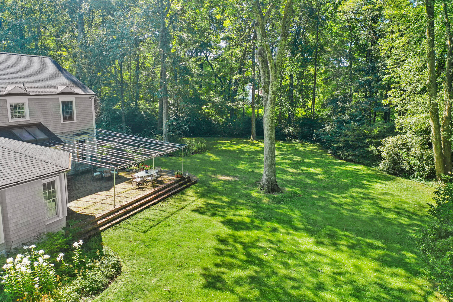 216 Turtle Back Road New Canaan, CT 06840 - Photo 32 of 38 a view of a chair and tables in the backyard of the house