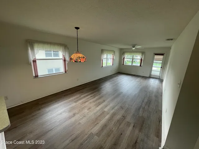 a view of an empty room with window and wooden floor