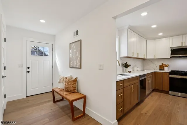 a kitchen with stainless steel appliances granite countertop a stove top oven a sink dishwasher and a refrigerator with wooden floor