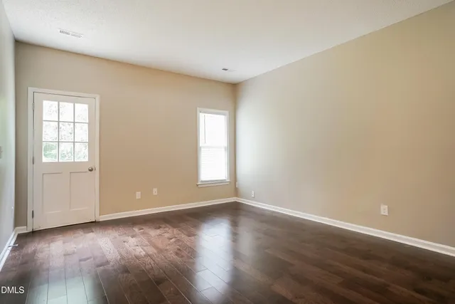 a view of an empty room with wooden floor and a window