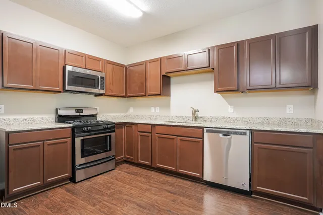 a kitchen with granite countertop wooden cabinets stainless steel appliances and a sink