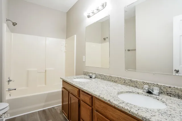 a bathroom with a granite countertop tub sink and mirror