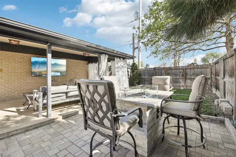 a roof deck with table and chairs a barbeque and a large tree