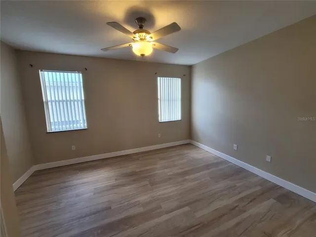 a view of an empty room with a window and wooden floor