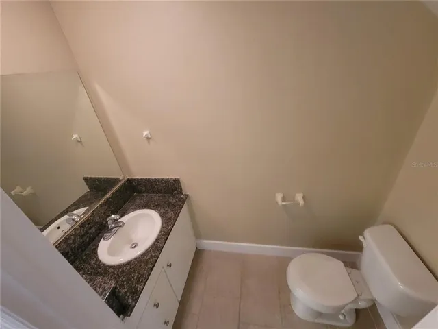 a bathroom with a granite countertop toilet and a sink