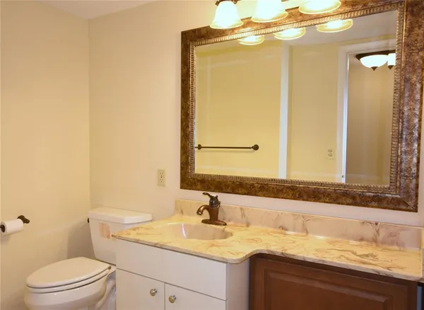 a bathroom with a granite countertop sink toilet and mirror