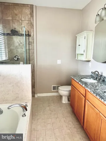 a bathroom with a granite countertop sink a toilet a mirror and shower