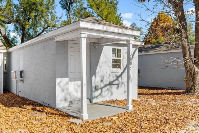 a view of a white house with large windows and wooden fence