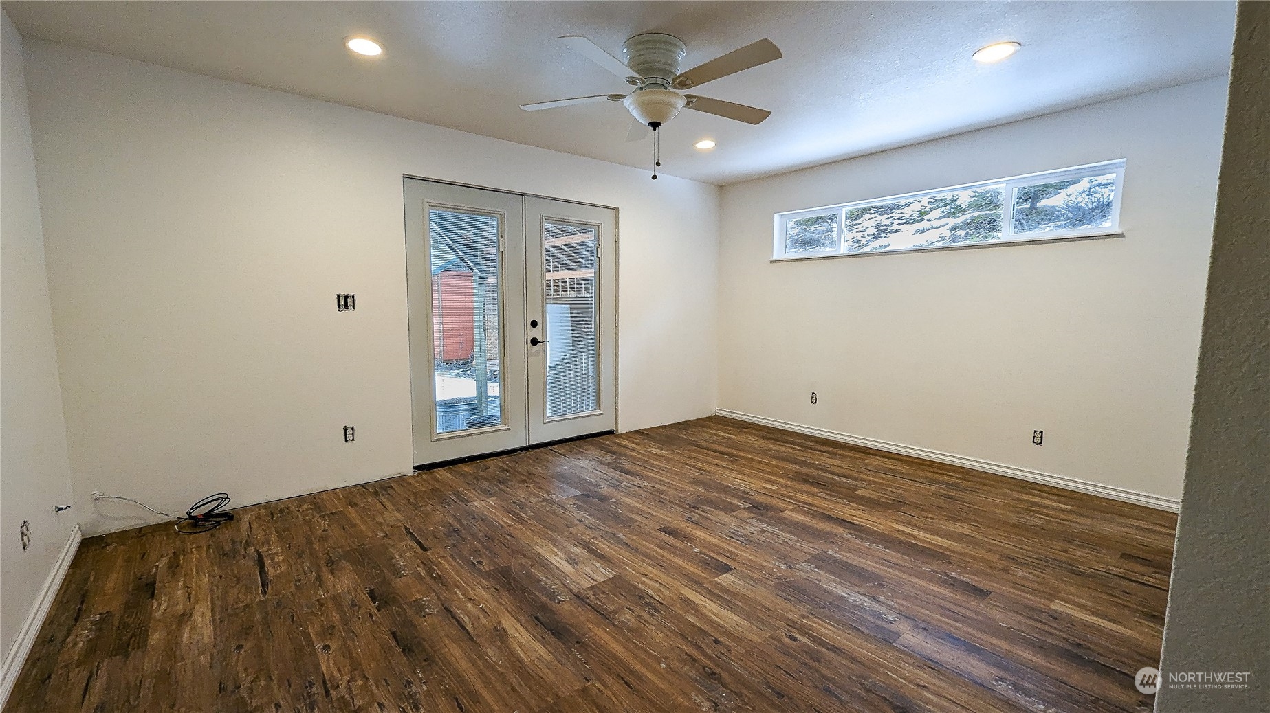 740 Cape Labelle Road Tonasket, WA 98855 - Photo 14 of 40 an empty room with wooden floor ceiling fan and windows