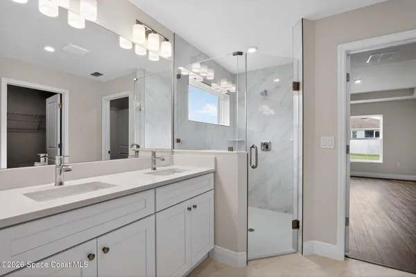 a bathroom with a double vanity sink mirror and next to a window