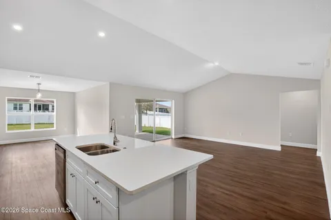 a kitchen with a stove a sink and wooden floor