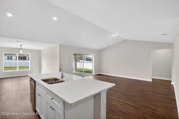a kitchen with a stove a sink and wooden floor