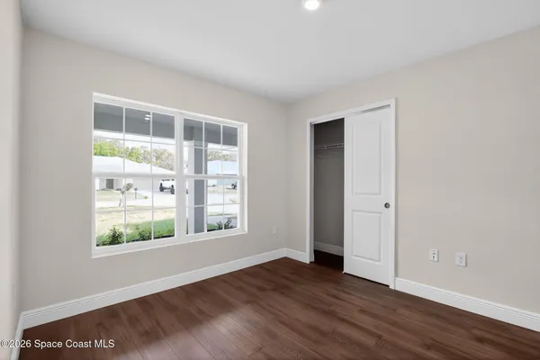 a view of an empty room with wooden floor and windows
