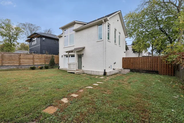 a white house that has a small yard and a large trees