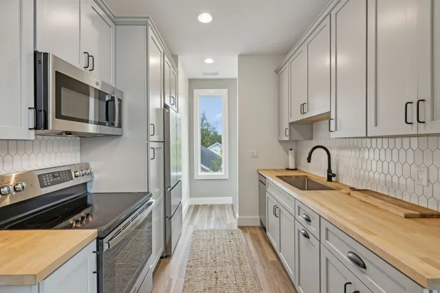 a kitchen with stainless steel appliances granite countertop a sink stove microwave and refrigerator
