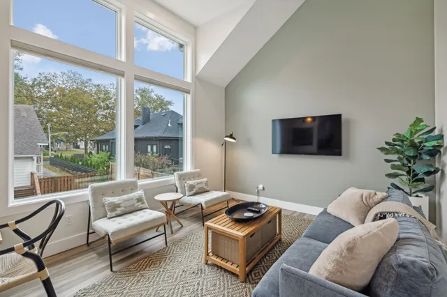 a living room with furniture a flat screen tv and a floor to ceiling window