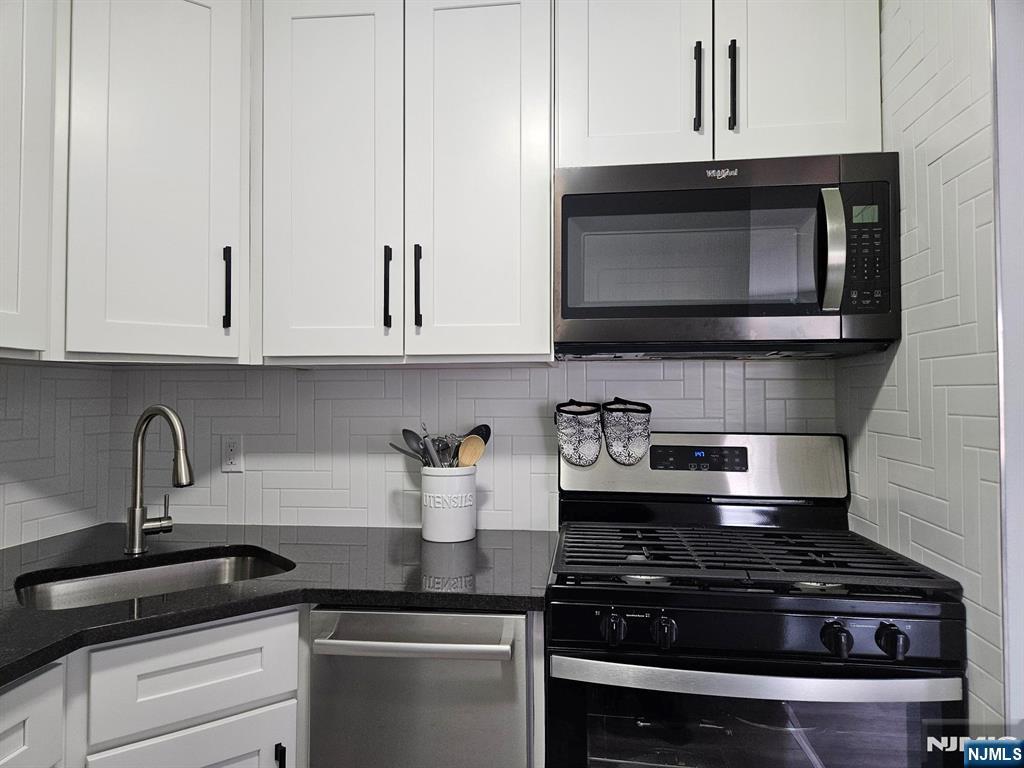 605 Grove Street, Unit F8 Clifton, NJ 07013 - Photo 11 of 15 a kitchen with stainless steel appliances granite countertop white cabinets and stove