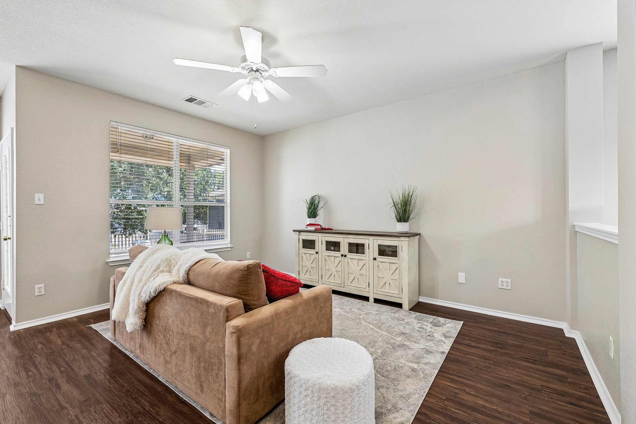 Warm wood flooring extends throughout this naturally illuminated living area.