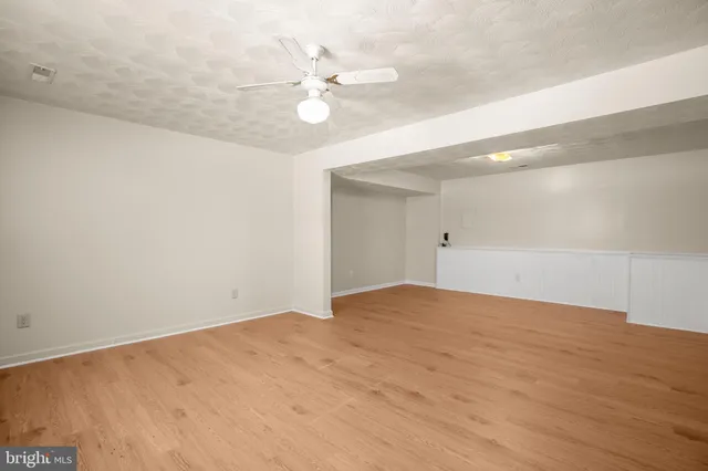 a view of an empty room with a chandelier fan