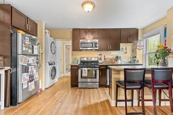 a kitchen with stainless steel appliances granite countertop a stove top oven a dining table and chairs with wooden floor