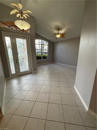 a view of an empty room with chandelier fan and windows