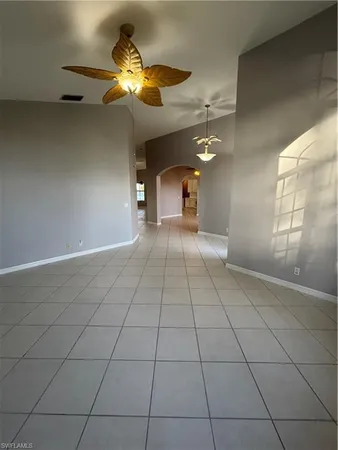 a view of an empty room and chandelier fan
