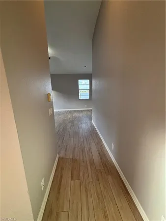 an empty room with wooden floor chandelier fan and windows