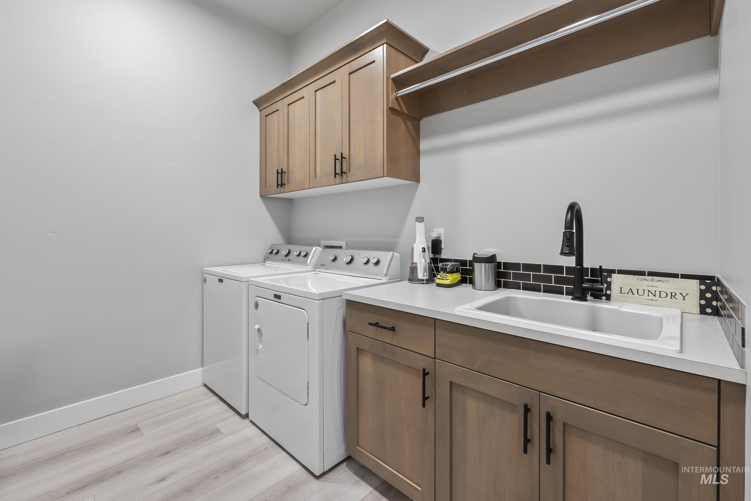 24696 Regal Road Middleton, ID 83644 - Photo 16 of 24 Laundry room featuring washer and clothes dryer, light wood finished floors, and cabinet space